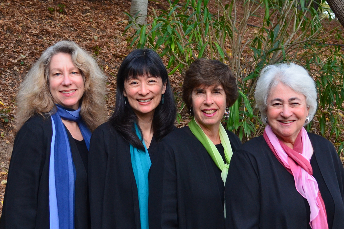 photo of four women wearing black shirts and colored scarves